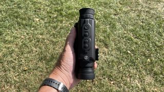 A Bushnell Equinox X650 Digital Night Vision monocular, in a hand, showing the buttons.