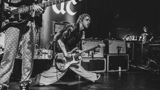 A black and white image of Carlos O&#039;Connell playing a Rory Gallagher Stratocaster onstage