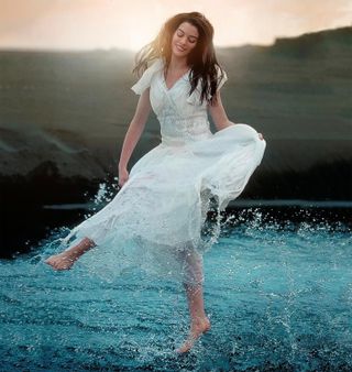 Anne Hathaway splashes in water in a white dress in the movie the other side of heaven