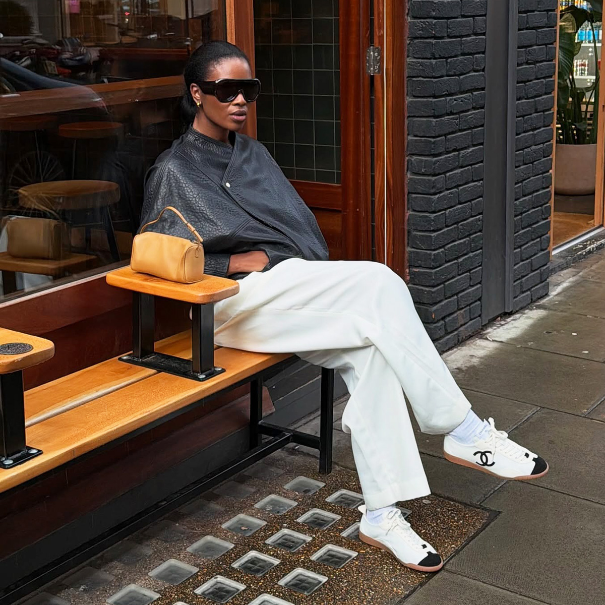 Influencer wearing a leather jacket, white pants, and sneakers