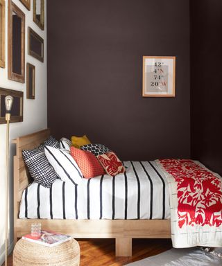 bedroom with dark purple wall, striped bedding and picture gallery wall