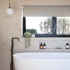 Terrazzo bathroom with white tub and freestanding black tap
