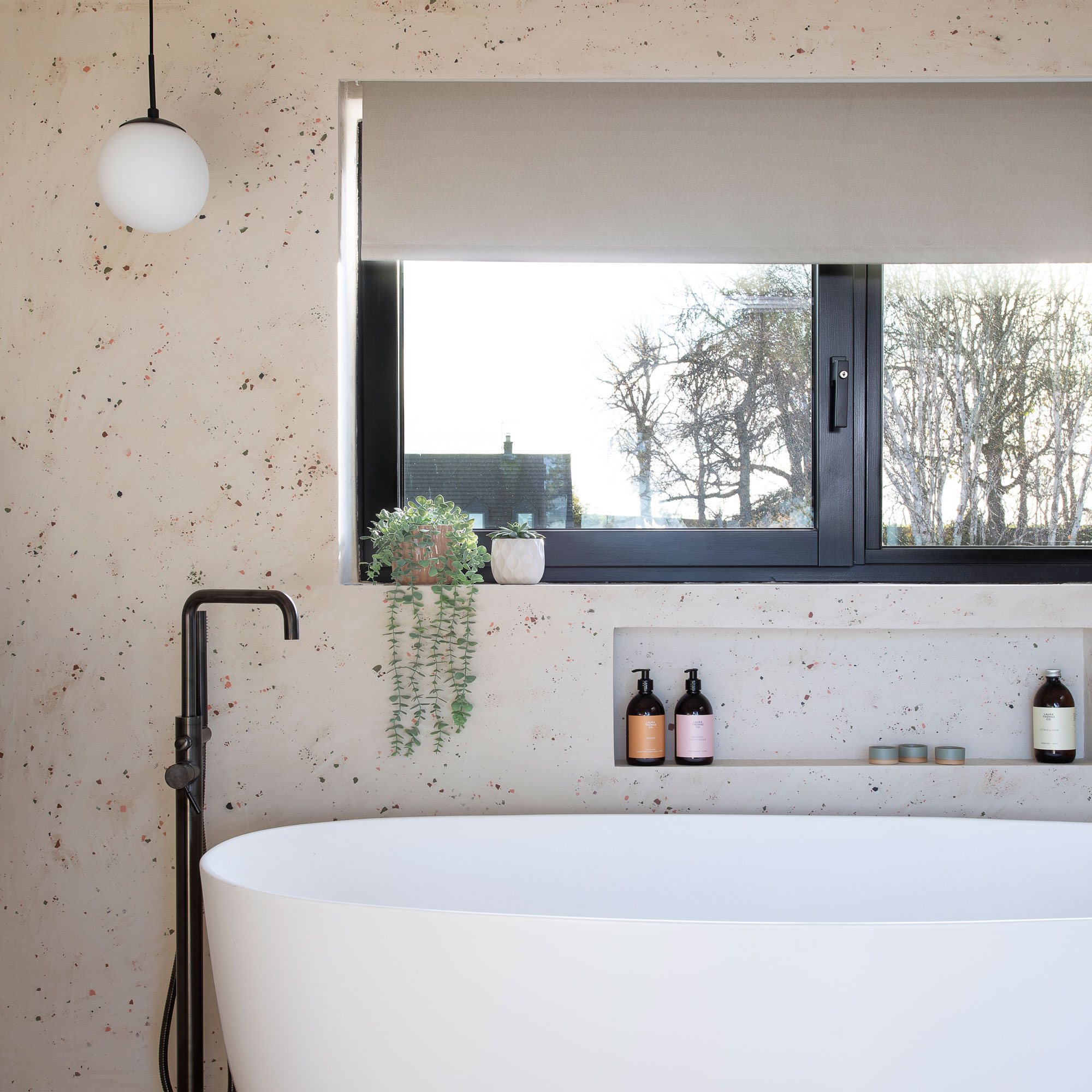Terrazzo bathroom with white tub and freestanding black tap