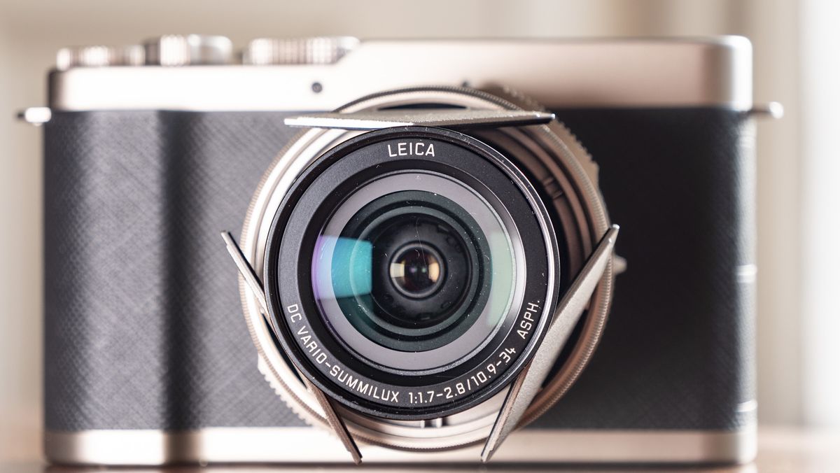 Close up of the lens, of the Titanium Gold special edition of the Panasonic Lumix L10 compact camera, on an antique wooden table