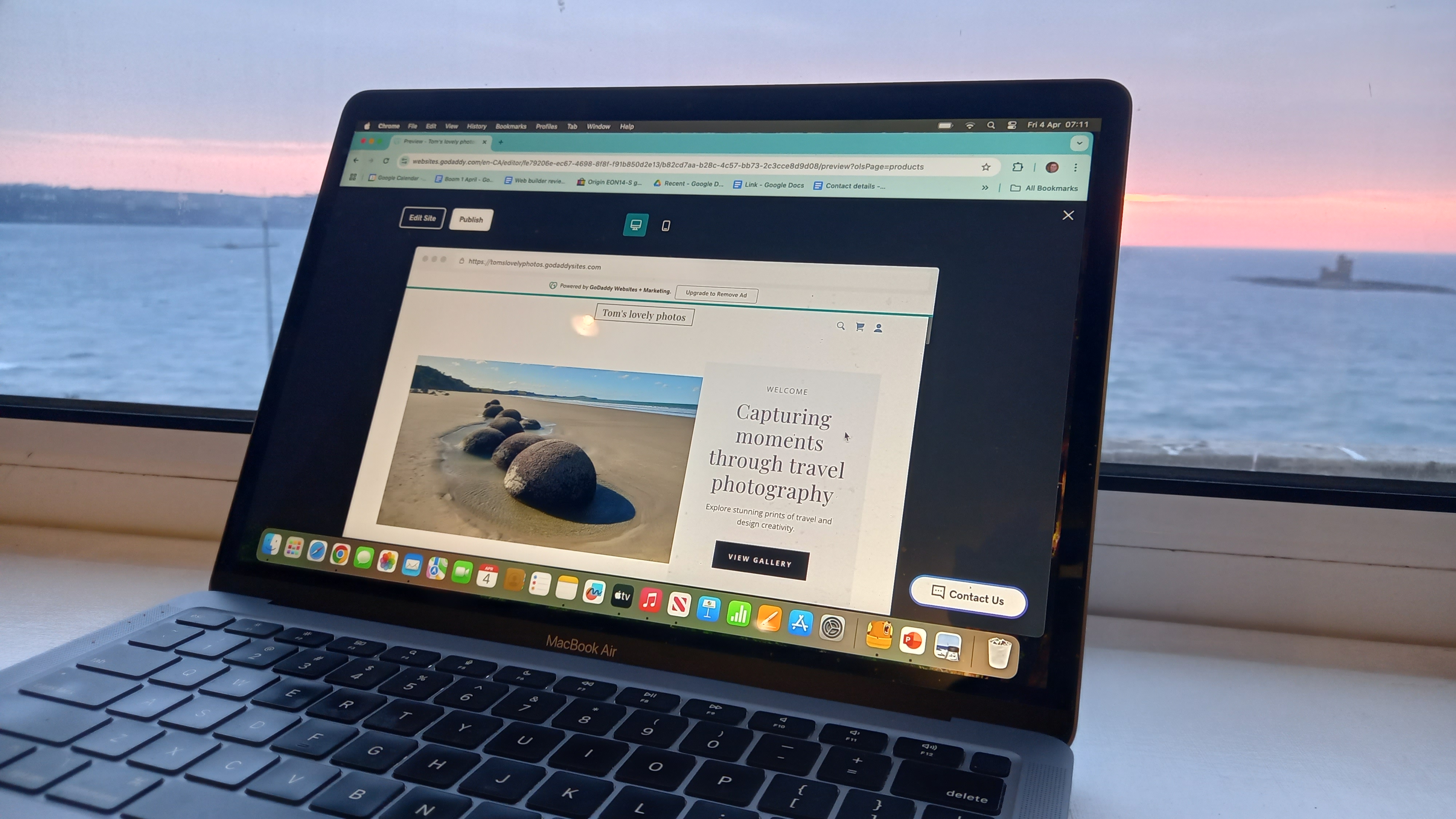 Laptop next to window overlooking the sea, featuring website being edited in GoDaddy interface