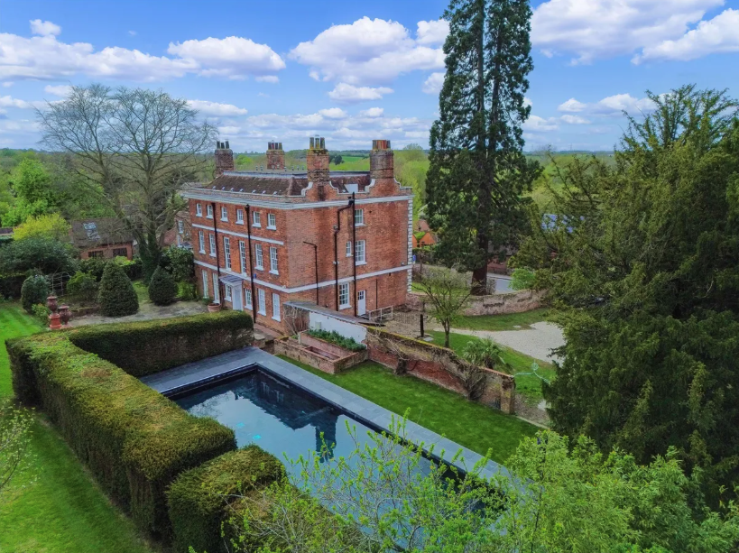 A view of the red-brick Queen Anne style Old Vicarage and swimming pool