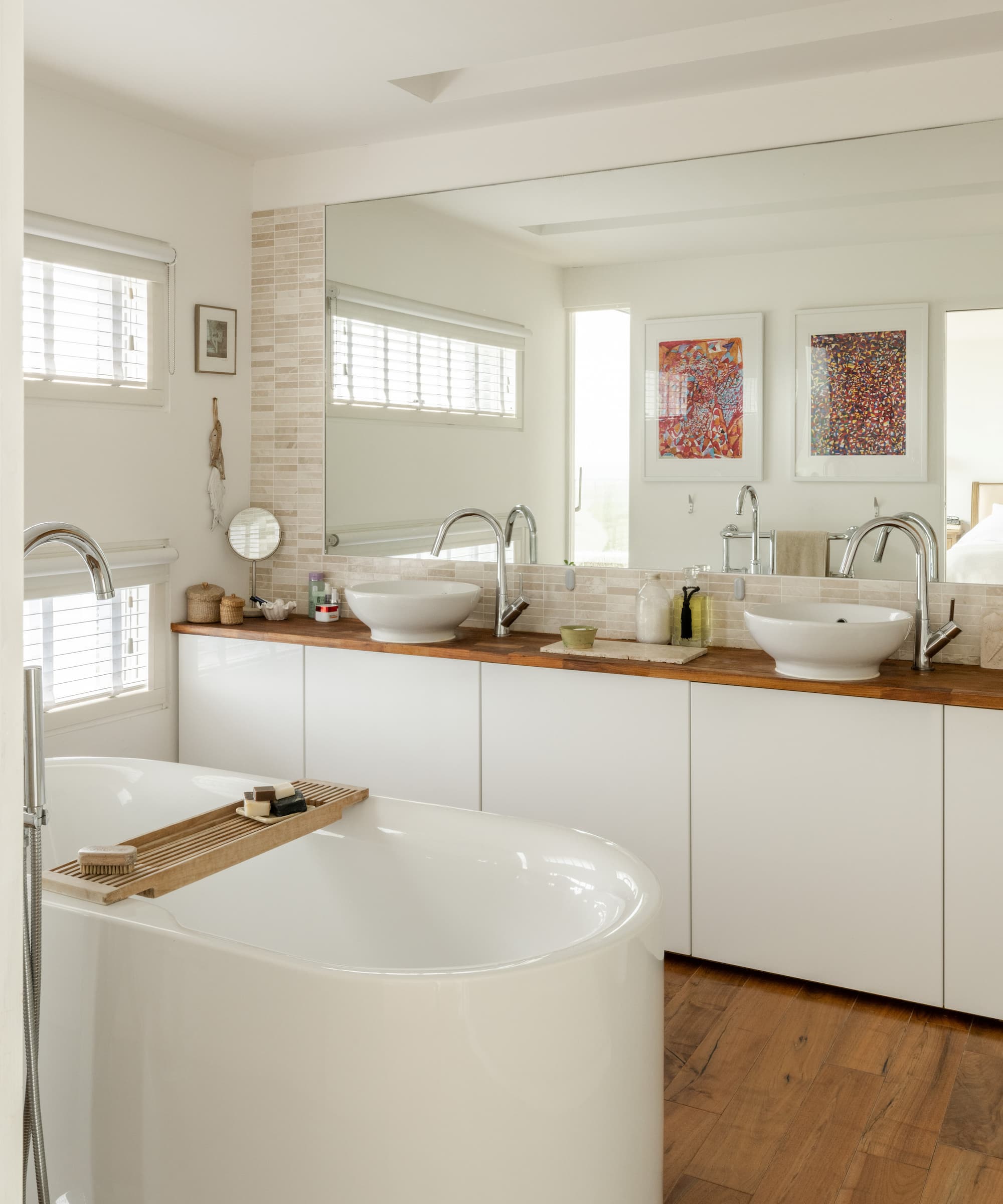 A white porcelain bath in a white bathroom with wooden flooring