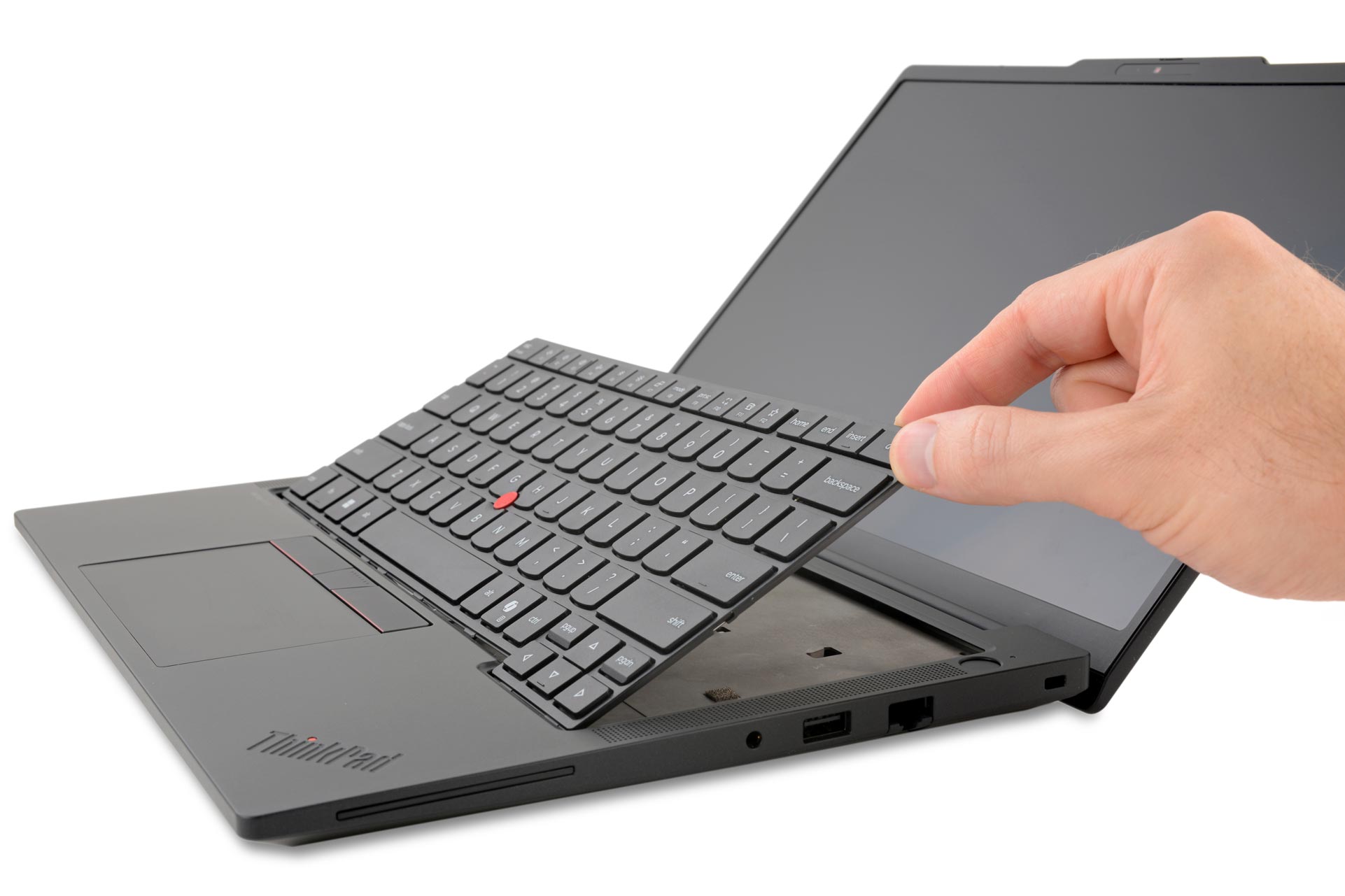 The hand lifts the keyboard from the Lenovo ThinkPad T14 Gen 7 laptop, showing off the repairable design. The laptop screen is tilted back. Mood is in focus, emphasizing functionality.