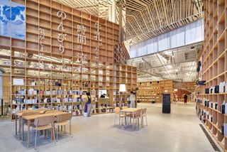 The Nasushiobara library reading room which features wood tables and floor to roof wood bookshelves.