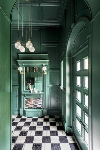 A black and white checkerboard flooring against olive green walls