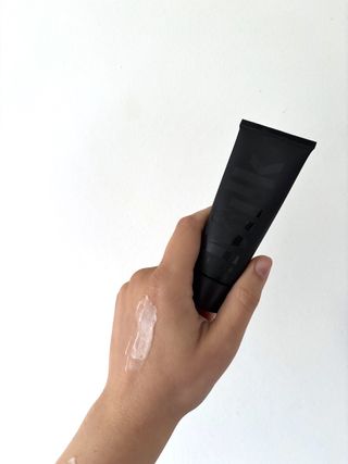 Mica Ricketts holding tube of Milk Makeup Pore Eclipse Mattifying Primer and showing swatch and texture of product