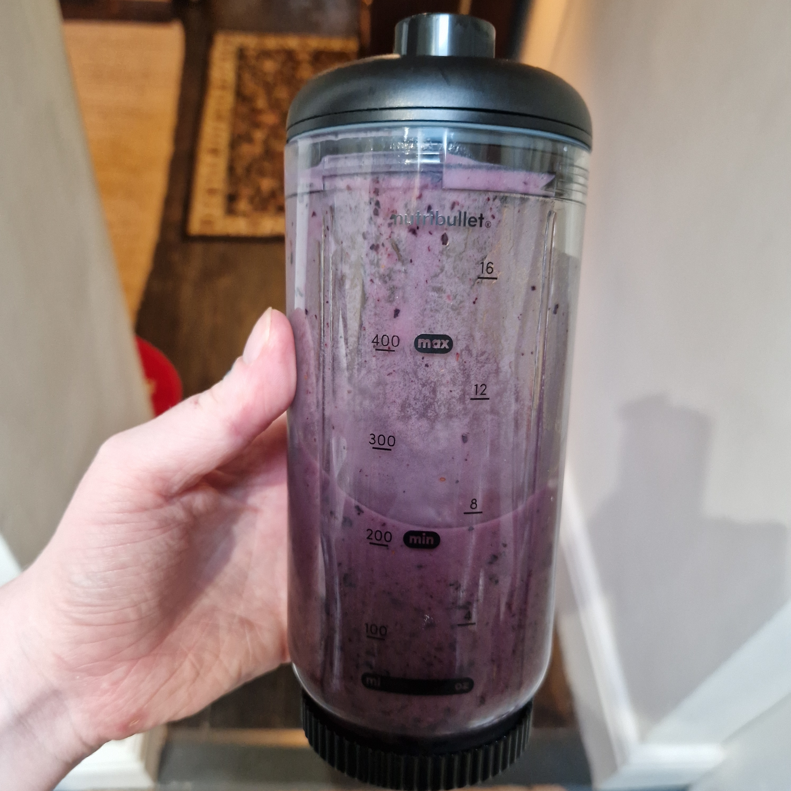 Hand holding blender jug filled with purple liquid