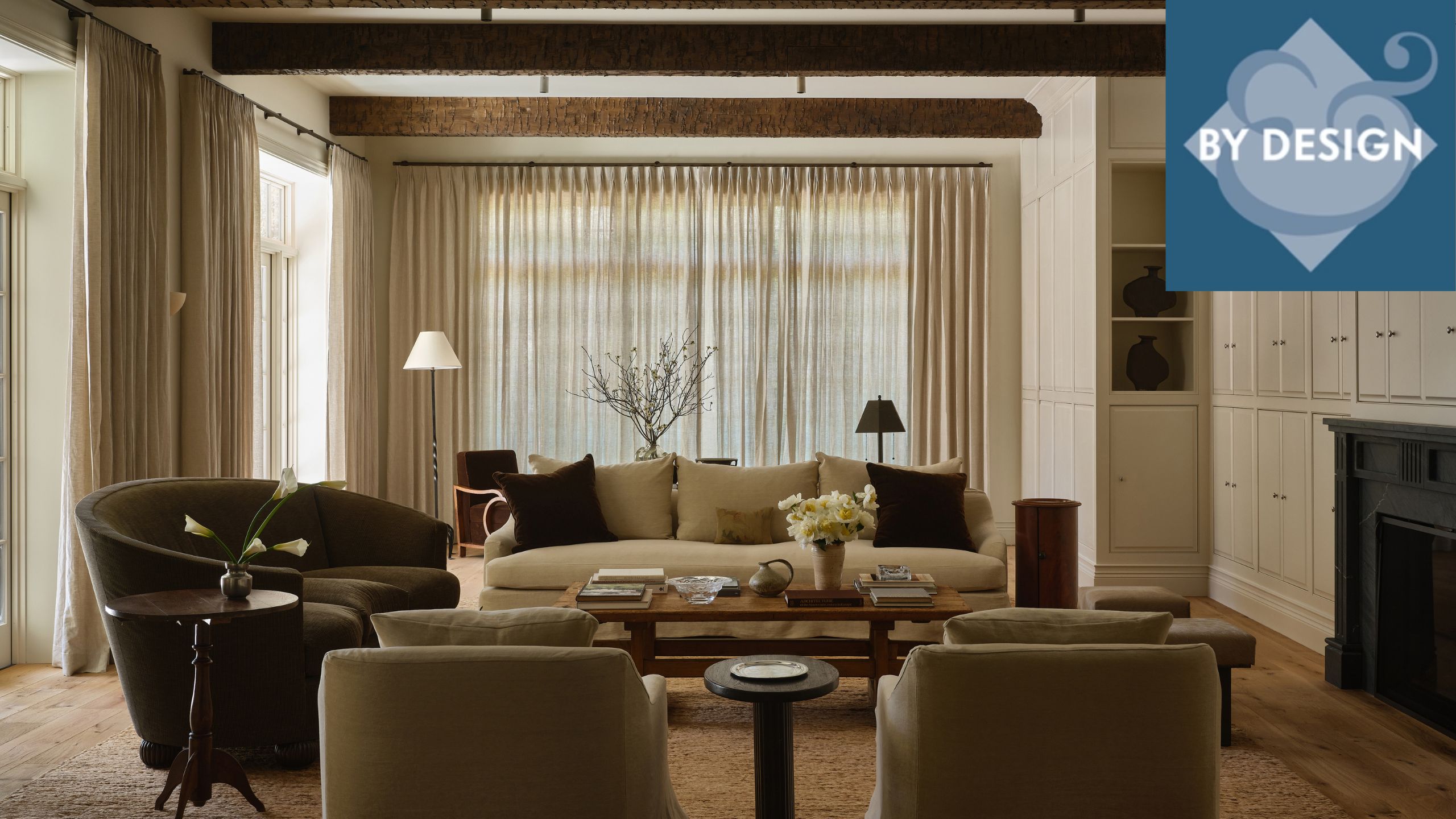 Cozy neutral living room with beamed wooden ceiling, sofa and armchairs surrounding a coffee table