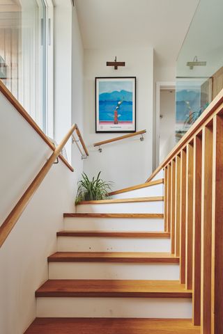white staircase with wood flooring and bannister