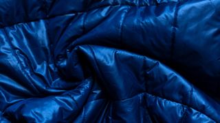 How to fluff a down jacket without a dryer: Close up of blue down material