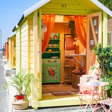 orange painted beach hut with palm plant outside