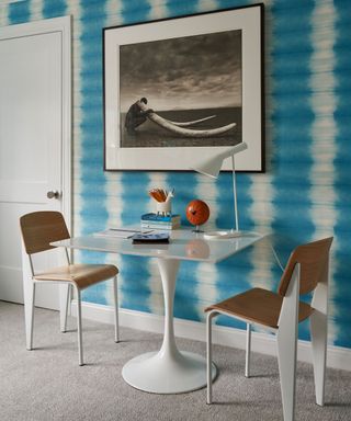 colorful children's bedroom with turquoise tie dye wallpaper, a square table and chairs and black and white photo