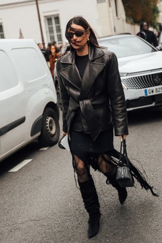 woman wearing leather jacket, skirt, and knee-high boots