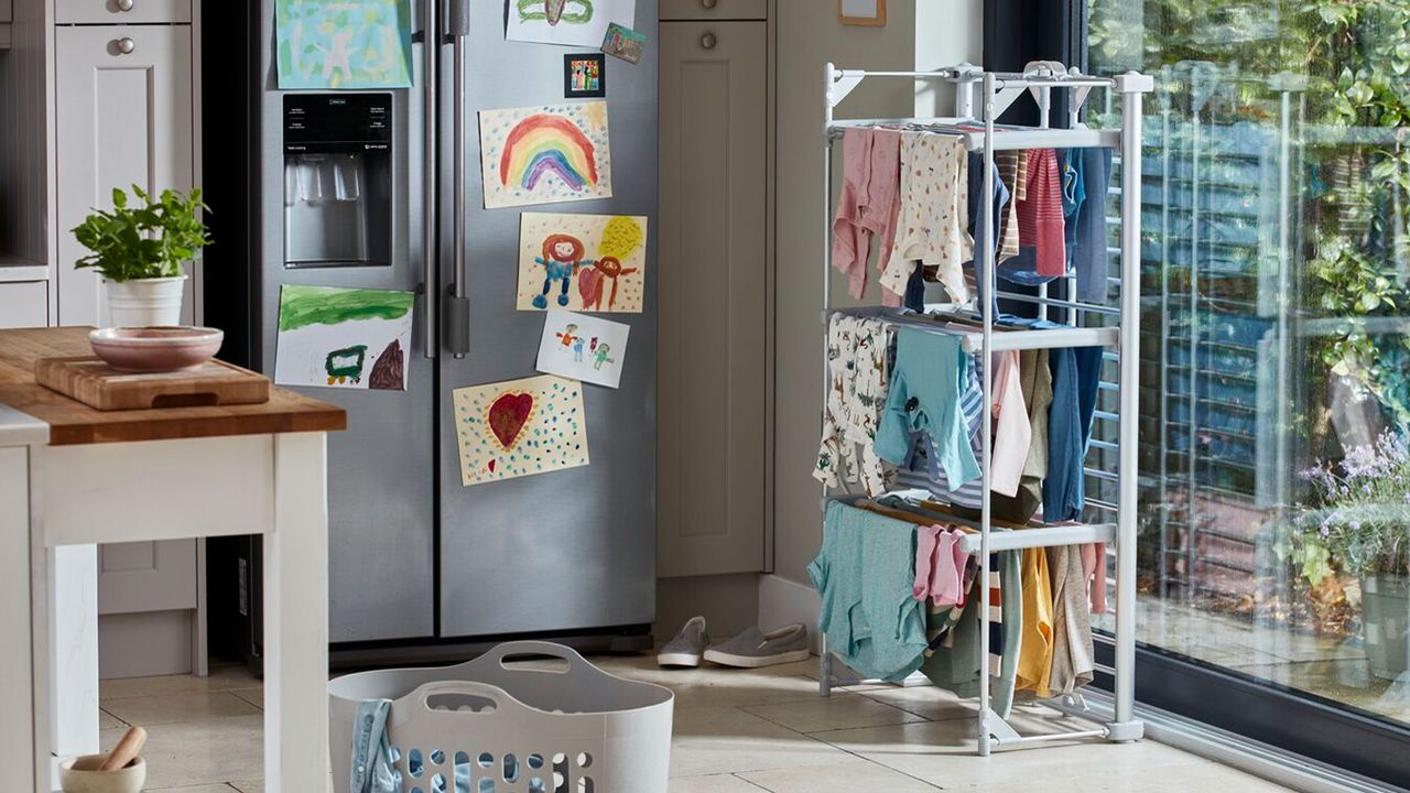 heated clothes airer full of clothes positioned in kitchen next to large fridge and window