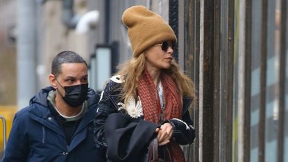 The Olsen twin wearing a similar-sized tan beanie, black coat, black pants, and red scarf in New York City on January 1, 2023.