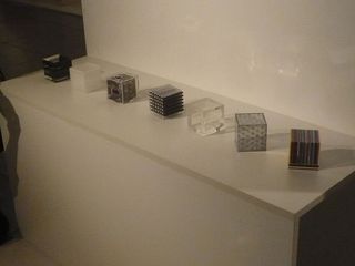 Seven different cubes sit on a white shelf