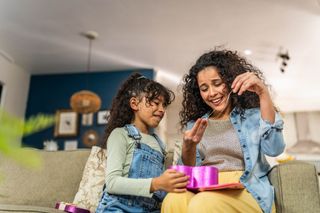 Child girl giving a gift to mother at home