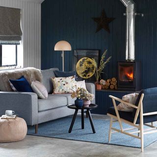 navy living room with grey sofa and log burner