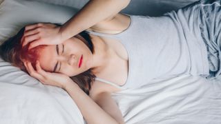 woman having headache while she lying on bed. - stock photo