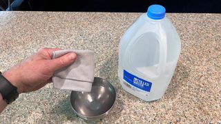 hand dipping cloth into distilled water on counter