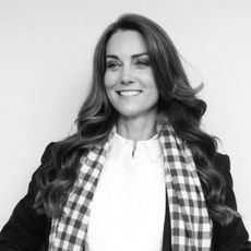 A black and white photo of Kate Middleton wearing a white shirt and checkered scarf with black blazer