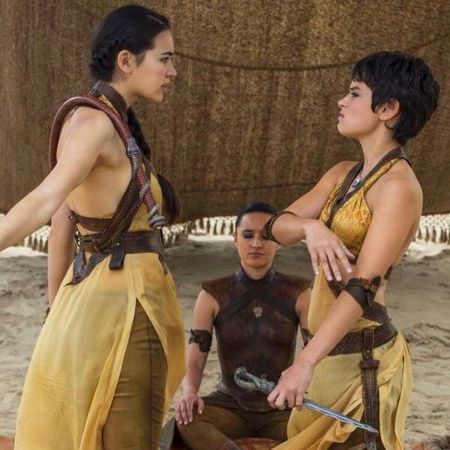 Two dark-haired women in mustard outfits arguing