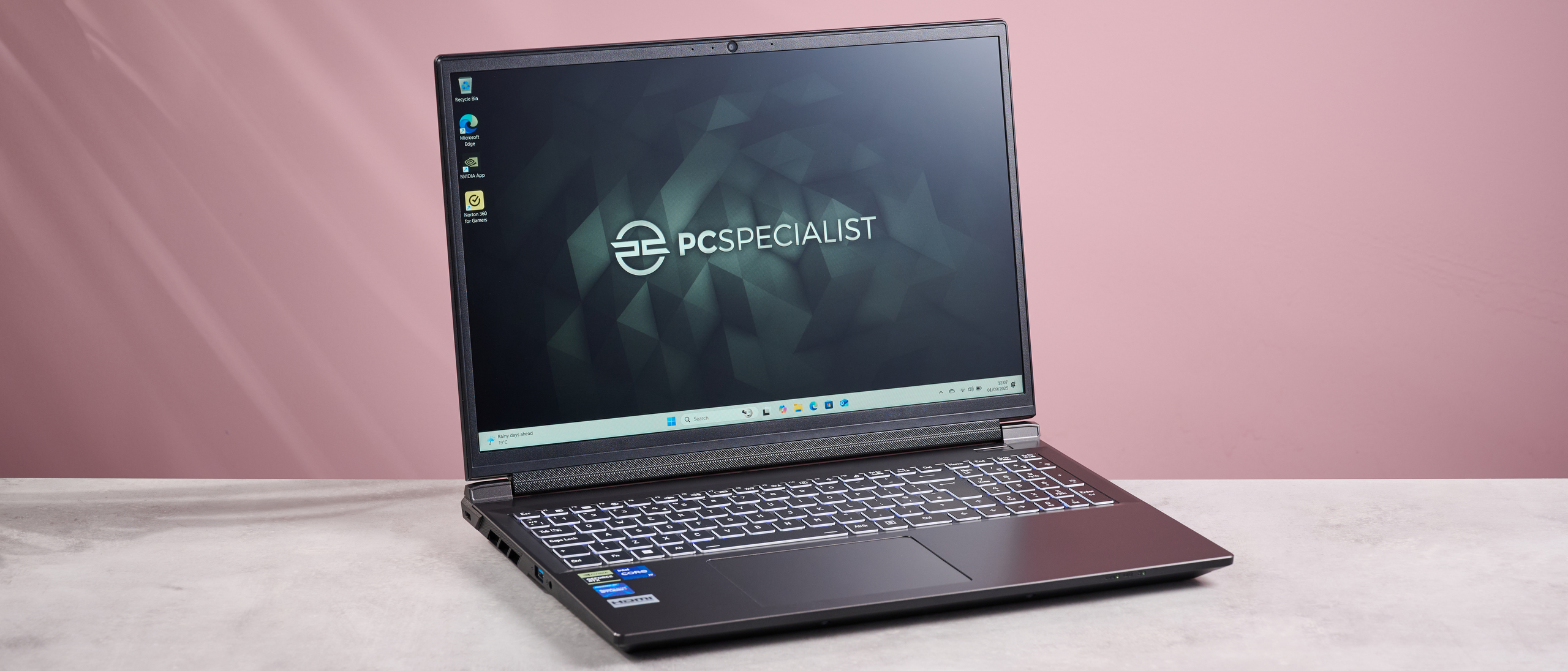 PC Specialist Defiance II 16 open on desk with pink background