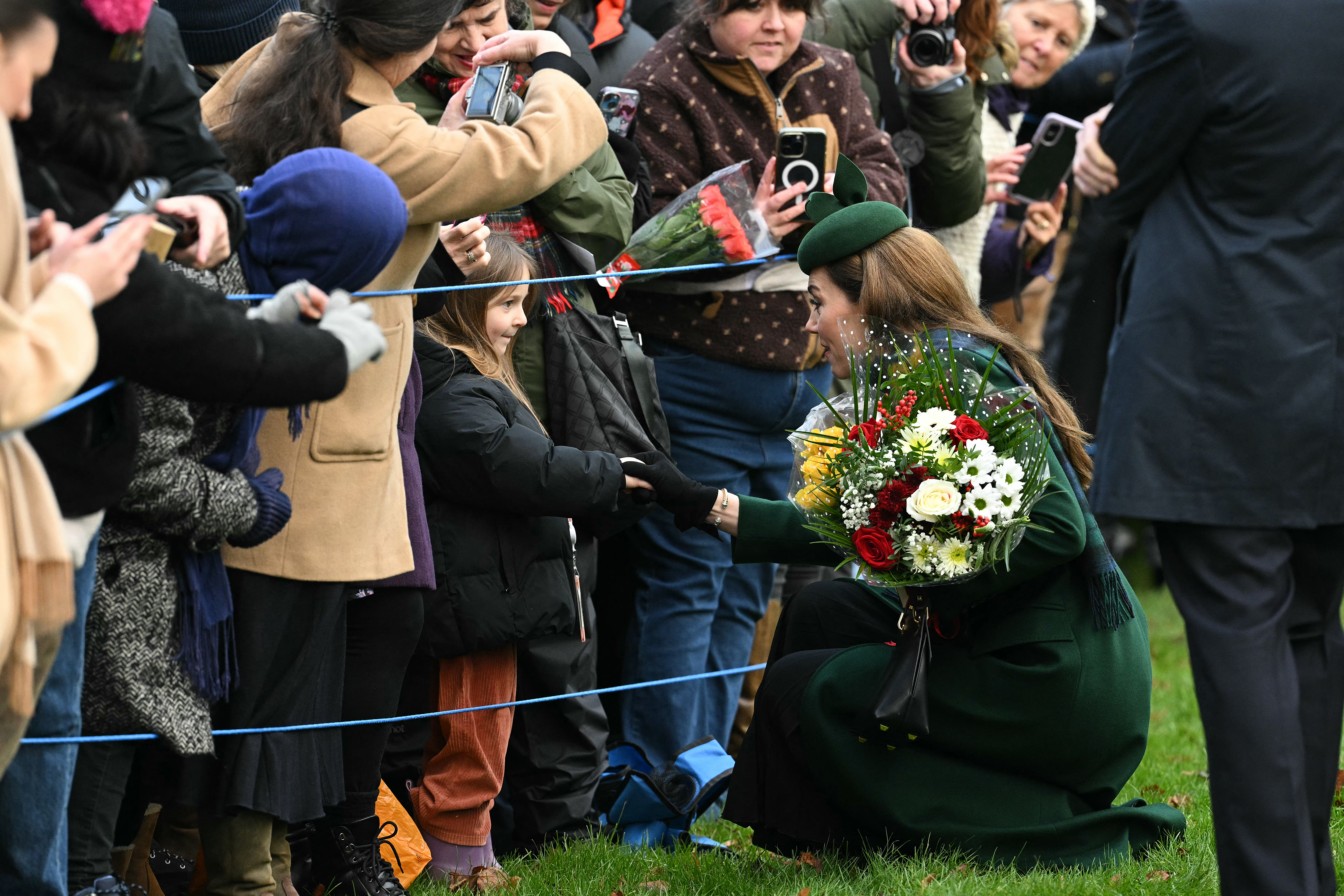 Kate Middleton wearing a green coat bending down to talk to a little girl on Christmas Day