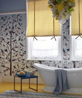 A bathroom with yellow and blue patterned wallpaper, and a blown glass chandelier
