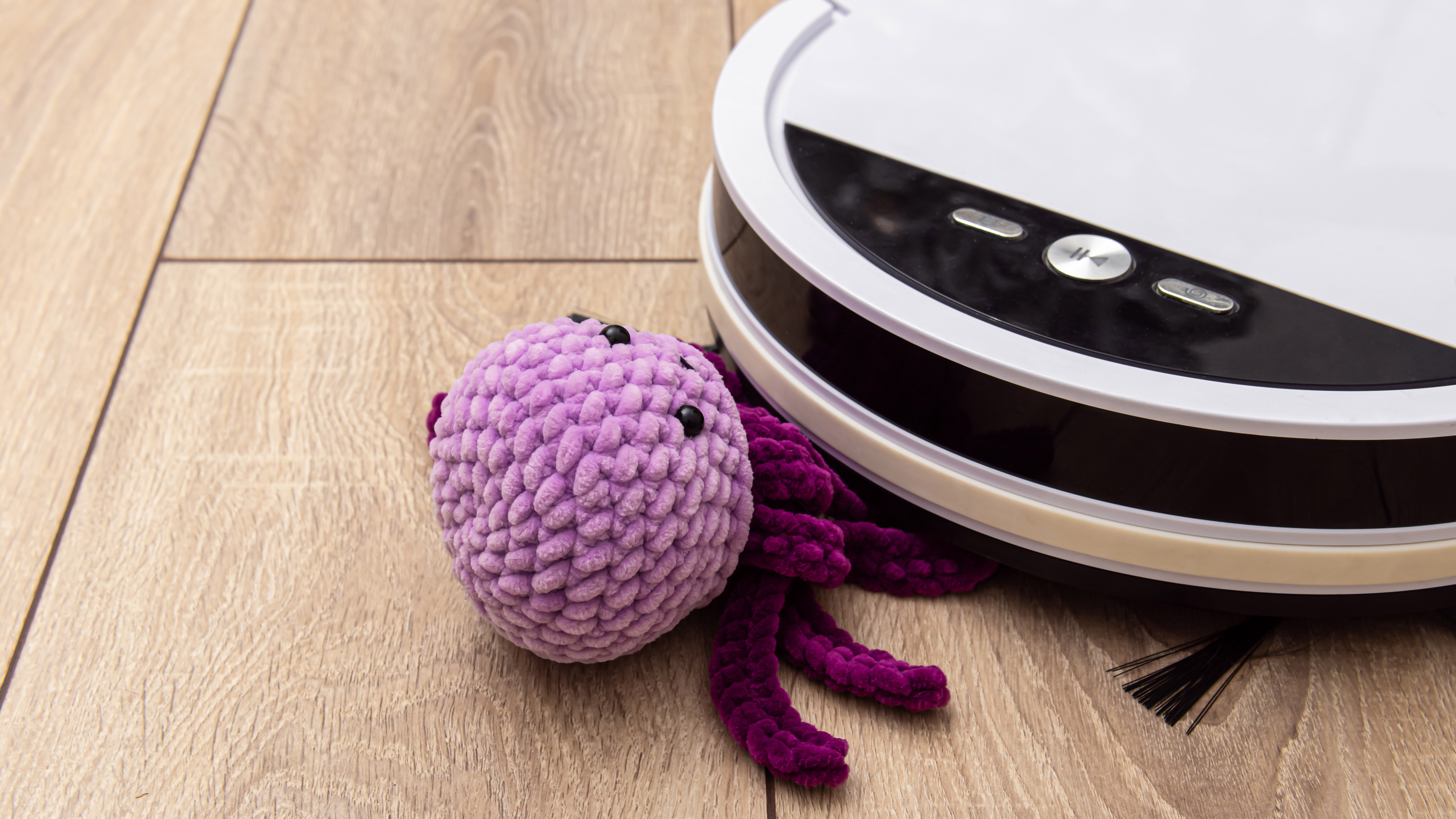 Purple toy stuck under white robot vacuum cleaner