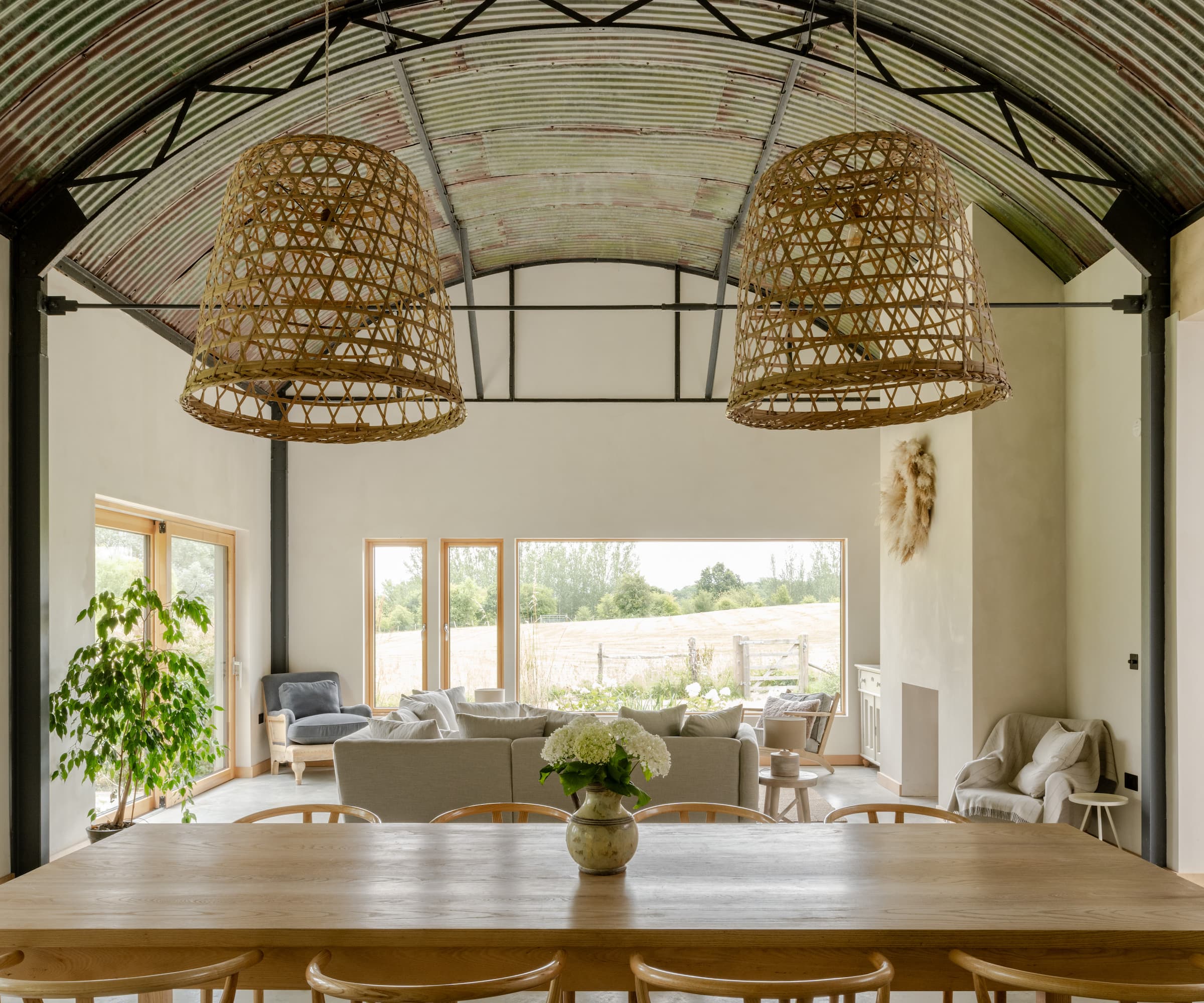 An open-plan living area with a wooden table and a Corten roof above