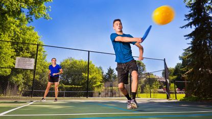 A young man and woman play pickleball as a team.