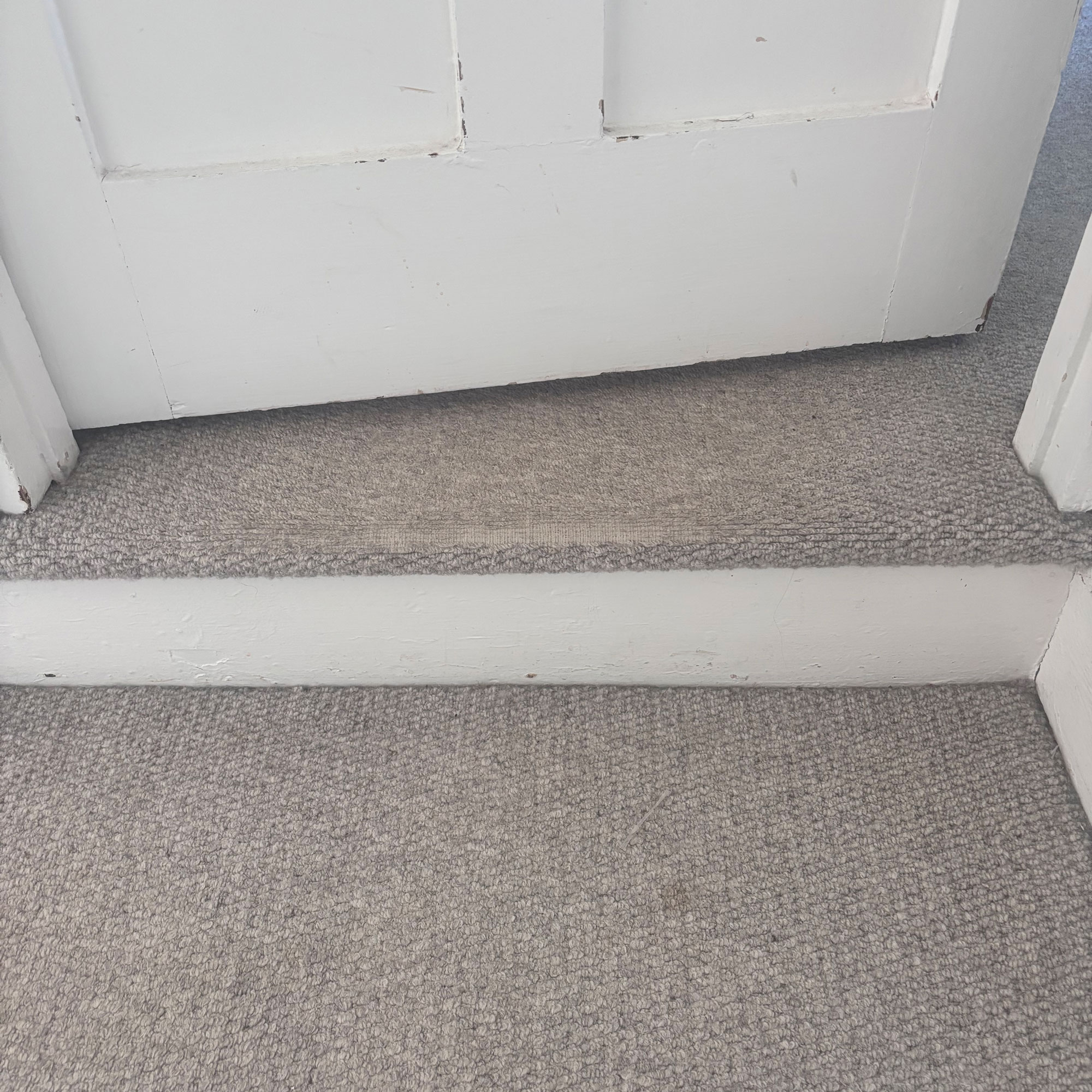 pale grey carpet with worn patch on step