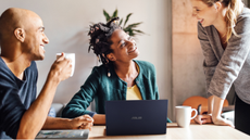 3 people standing around a ASUS laptop