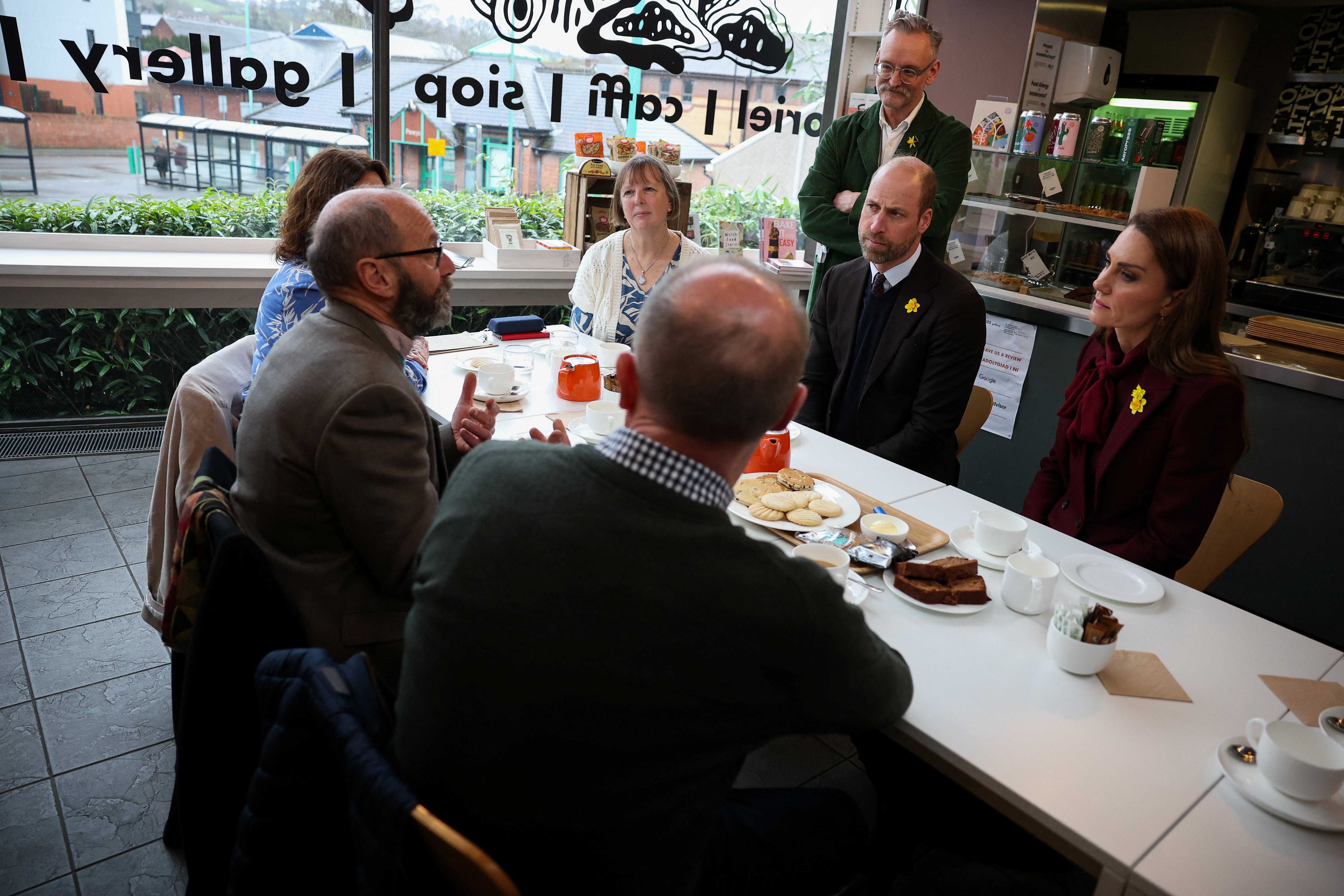 Prince William and Princess Kate sitting at a table with people at a cafe