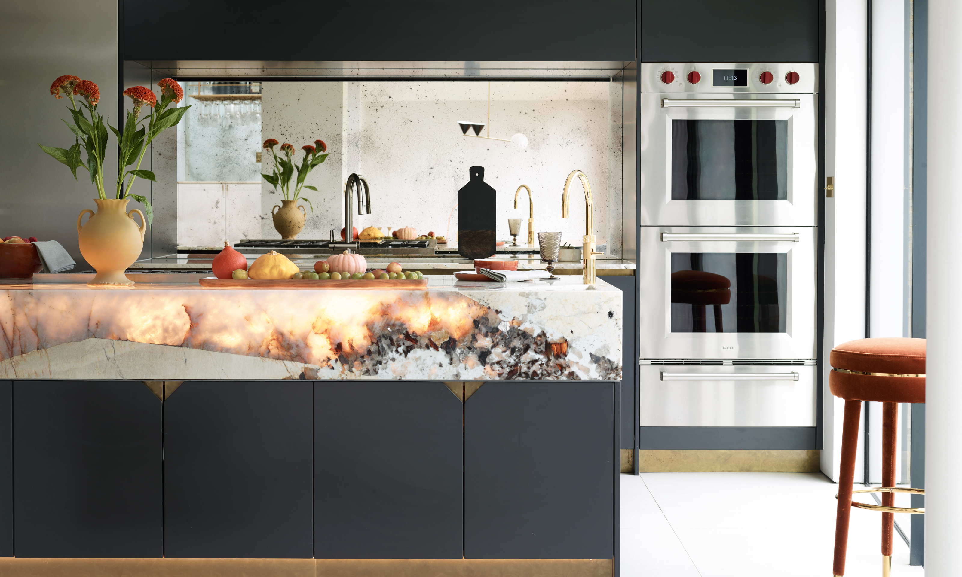 Sleek black kitchen with deep white marble worktop with backlit stone elements