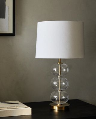 A lamp with a glass bubble base and cotton shade
