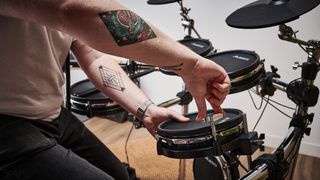 Man tightens Alesis Command Mesh drum head with a drum key