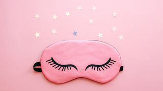 pink eye mask on pink background with silver stars