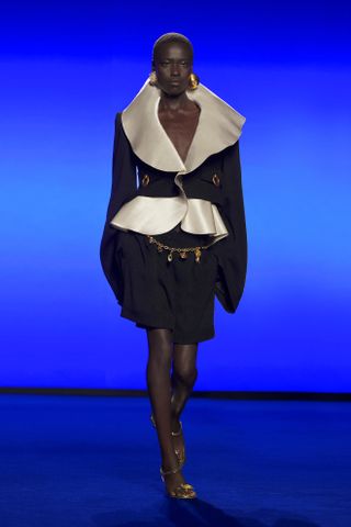 A model at Schiaparelli on the runway during the spring/summer 2025 season wearing a black-and-white large-collar jacket and skirt.