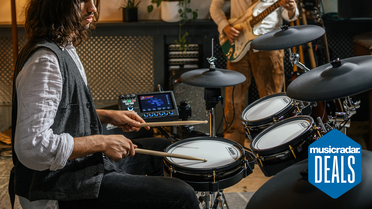 Man in a waistcoat and shirt playing an Alesis Strata Core kit with a band