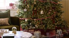 Festive living room scene featuring a warmly lit Christmas tree decorated with bows, red beaded garland, and clip-on candle ornaments.