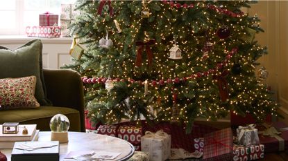 Festive living room scene featuring a warmly lit Christmas tree decorated with bows, red beaded garland, and clip-on candle ornaments.