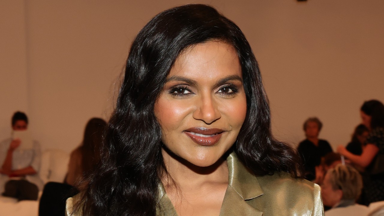 a woman with dark hair wearing a gold blazer dress