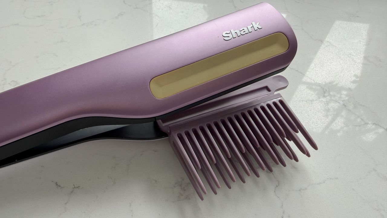 Close-up of the Shark SilkiPro Straight with the wide-tooth comb attachment clipped in, showing the gold cool-touch strip and Shark logo